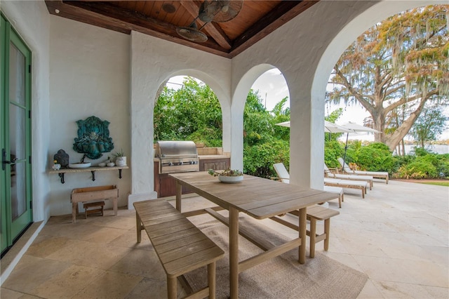 view of patio featuring ceiling fan, area for grilling, and exterior kitchen