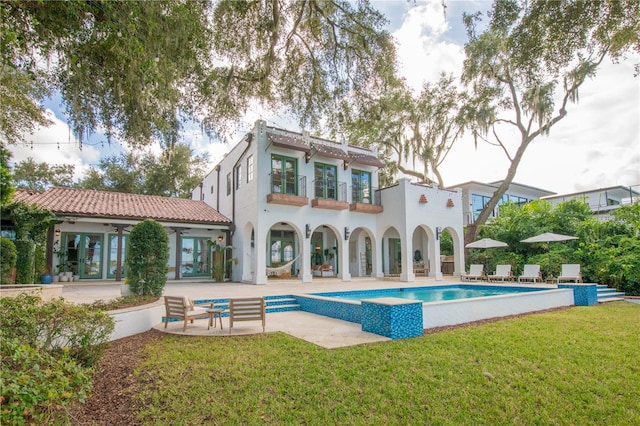 back of property featuring a patio, a balcony, and a lawn