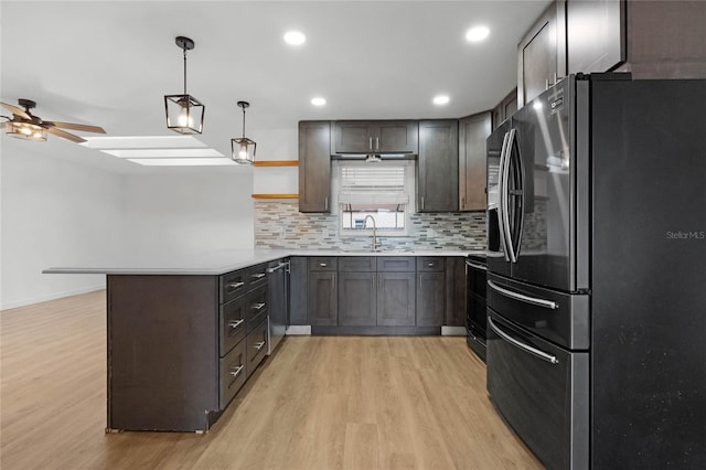 kitchen with tasteful backsplash, light hardwood / wood-style flooring, kitchen peninsula, pendant lighting, and appliances with stainless steel finishes