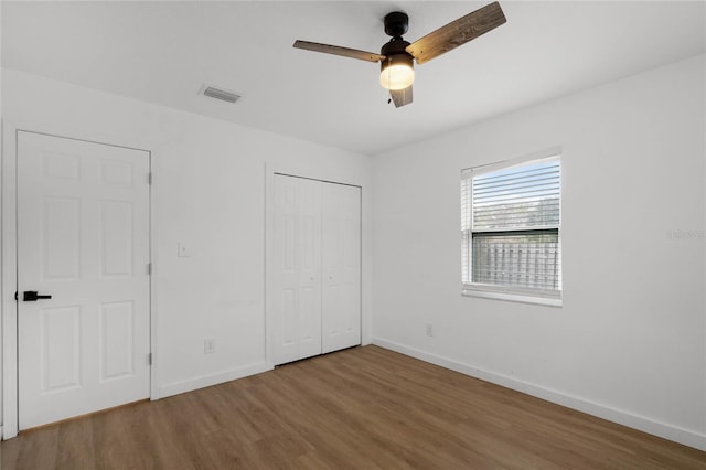 unfurnished bedroom featuring ceiling fan, a closet, and wood-type flooring