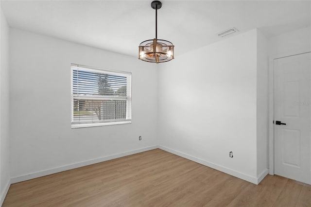 empty room with an inviting chandelier and light hardwood / wood-style flooring