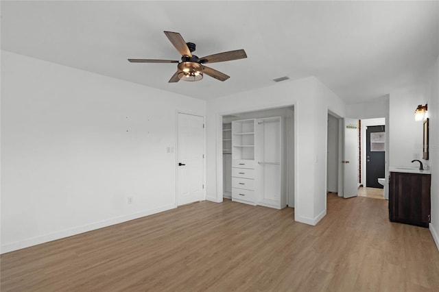 unfurnished bedroom featuring ensuite bathroom, sink, ceiling fan, light hardwood / wood-style floors, and a closet