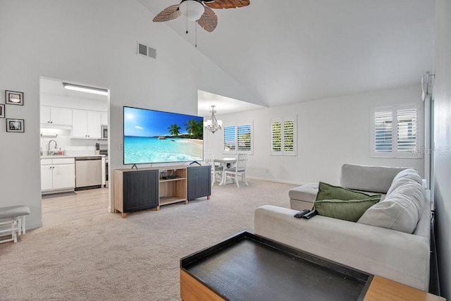 living room with ceiling fan with notable chandelier, light colored carpet, a healthy amount of sunlight, and sink