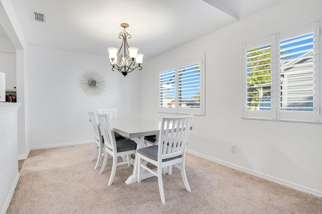 carpeted dining space featuring an inviting chandelier