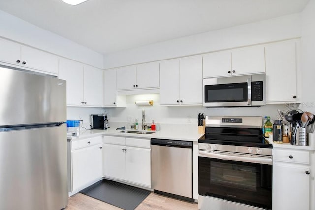 kitchen with sink, light wood-type flooring, white cabinets, and appliances with stainless steel finishes