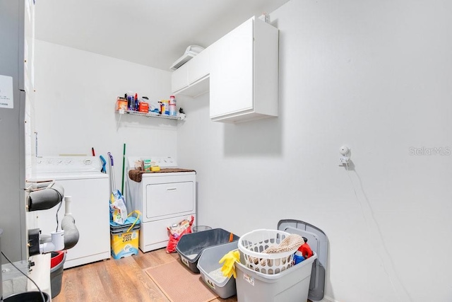 laundry room with cabinets, washer and dryer, and light hardwood / wood-style flooring