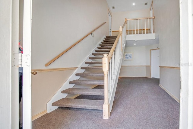 stairway featuring carpet flooring and a high ceiling