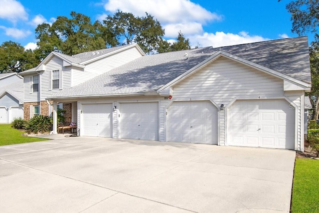 view of front facade with an attached garage, a shingled roof, concrete driveway, and brick siding