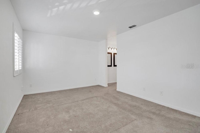 unfurnished room featuring carpet floors, visible vents, and baseboards