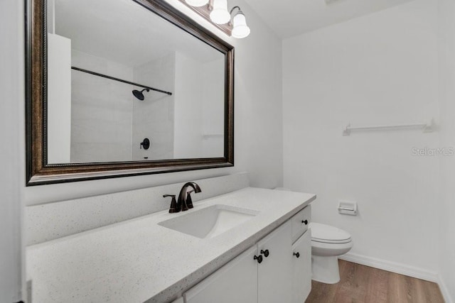 full bath with toilet, baseboards, wood finished floors, and vanity