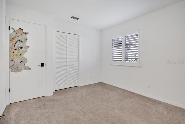 unfurnished bedroom with a closet, visible vents, and carpet flooring