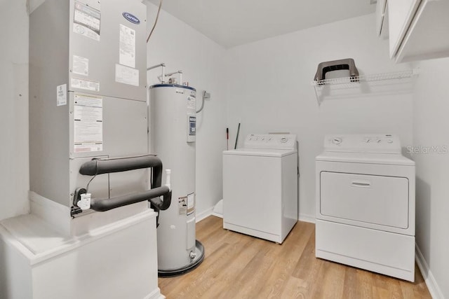 laundry area with washer and clothes dryer, light wood finished floors, electric water heater, laundry area, and baseboards