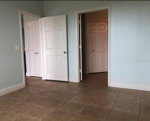 unfurnished bedroom with a closet and dark tile patterned floors