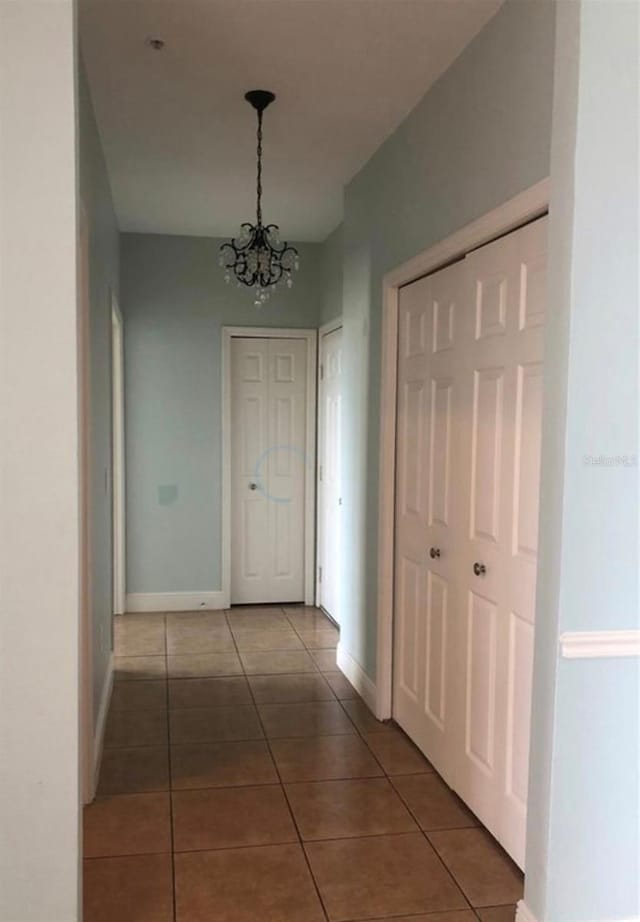 hall featuring tile patterned floors and an inviting chandelier