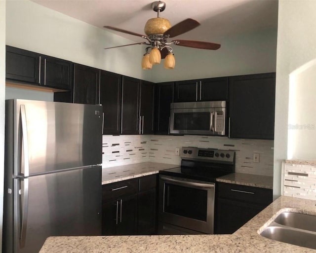 kitchen featuring light stone countertops, appliances with stainless steel finishes, decorative backsplash, and ceiling fan