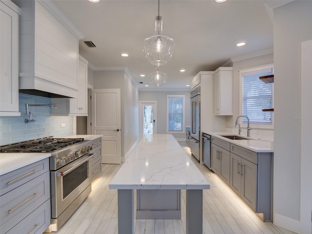 kitchen featuring tasteful backsplash, sink, high quality appliances, white cabinets, and hanging light fixtures