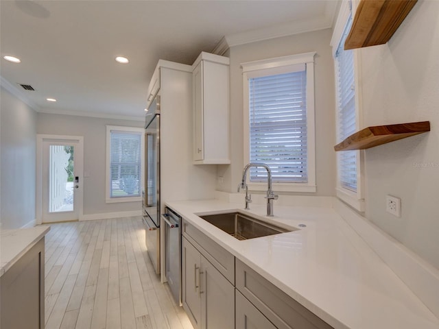 kitchen featuring crown molding, sink, dishwasher, and light wood-type flooring