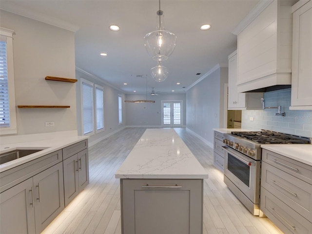 kitchen featuring gray cabinetry, crown molding, high end range, and light hardwood / wood-style floors