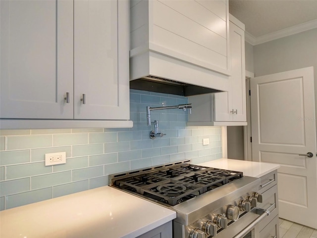 kitchen featuring custom exhaust hood, backsplash, crown molding, high end stove, and white cabinetry