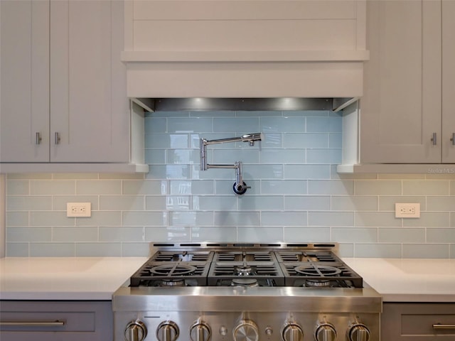 kitchen featuring stove, tasteful backsplash, and gray cabinets