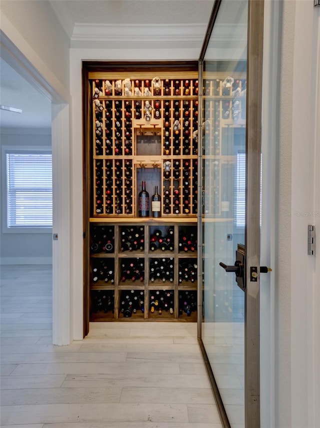 wine area featuring wood-type flooring and crown molding