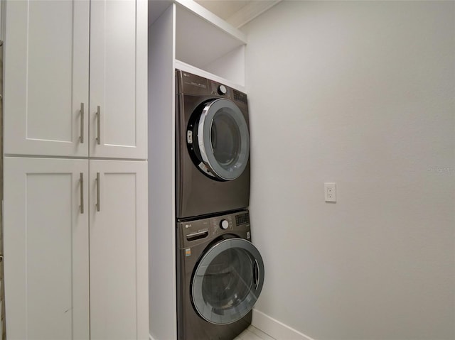 washroom with cabinets and stacked washing maching and dryer