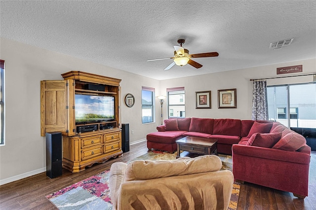 living room with a textured ceiling, ceiling fan, and dark hardwood / wood-style floors