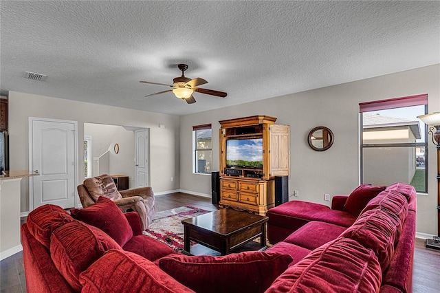 living room with a textured ceiling, ceiling fan, and dark hardwood / wood-style floors