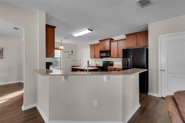 kitchen featuring a kitchen breakfast bar, black appliances, kitchen peninsula, dark wood-type flooring, and a textured ceiling