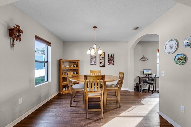 dining space with an inviting chandelier, a textured ceiling, and dark wood-type flooring