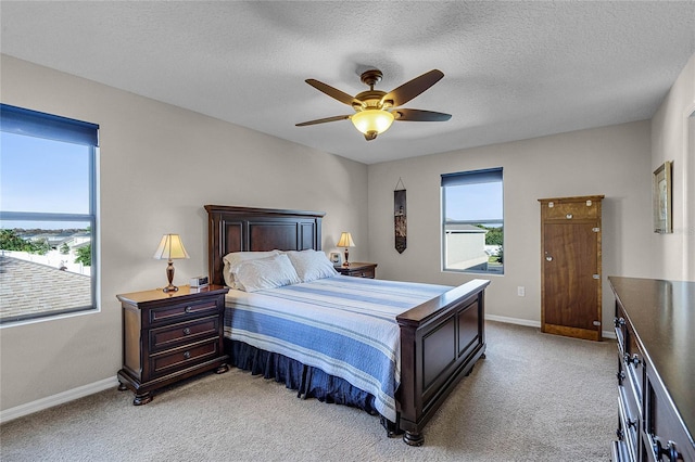 bedroom featuring light carpet, ceiling fan, and a textured ceiling