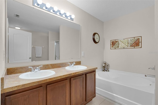 bathroom with a tub, a textured ceiling, tile patterned floors, and vanity