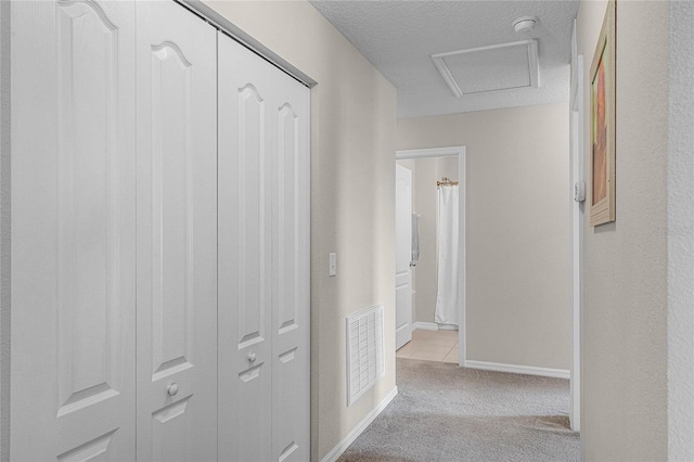 corridor with a textured ceiling and light carpet