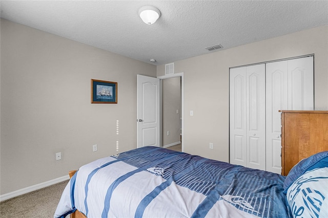 bedroom with a textured ceiling, carpet floors, and a closet