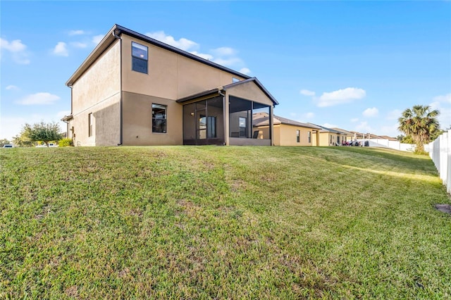 rear view of house featuring a lawn and a sunroom