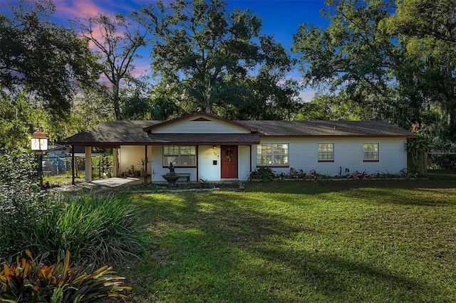 ranch-style home with covered porch and a lawn