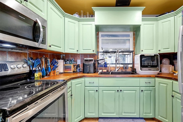 kitchen featuring wood counters, backsplash, stainless steel appliances, and sink