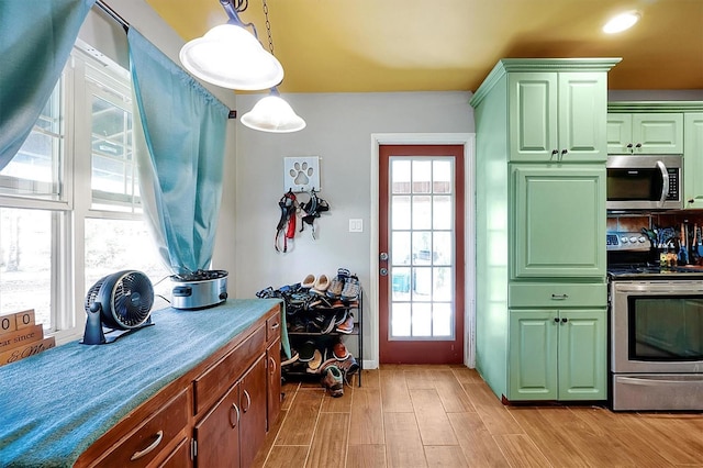 interior space featuring light hardwood / wood-style floors, pendant lighting, stainless steel appliances, and green cabinetry