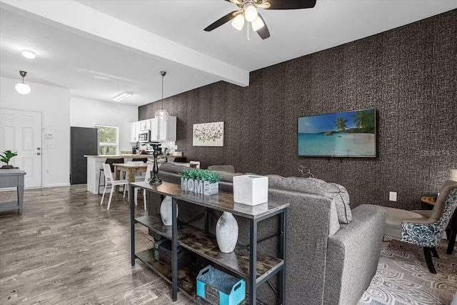 living room with ceiling fan, beamed ceiling, and hardwood / wood-style flooring