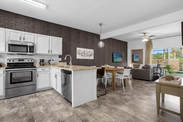 kitchen featuring white cabinetry, sink, hanging light fixtures, kitchen peninsula, and appliances with stainless steel finishes