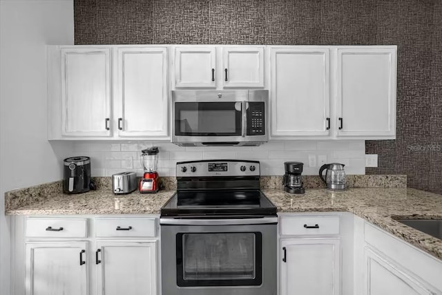 kitchen with backsplash, white cabinets, and stainless steel appliances