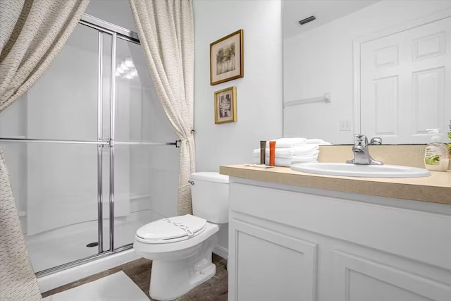 bathroom with vanity, toilet, and a shower with door