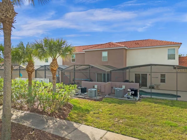 back of property featuring glass enclosure, a lawn, and central air condition unit