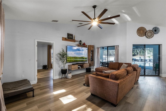 living room with high vaulted ceiling, ceiling fan, a wealth of natural light, and light hardwood / wood-style flooring