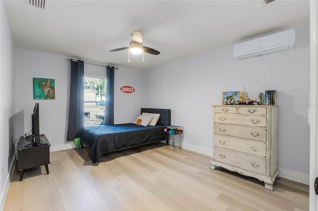 bedroom with a wall mounted air conditioner, light hardwood / wood-style floors, and ceiling fan