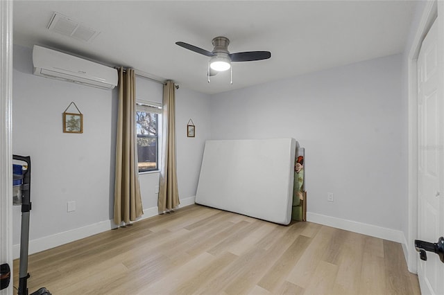 bedroom with ceiling fan, a wall mounted air conditioner, and light wood-type flooring