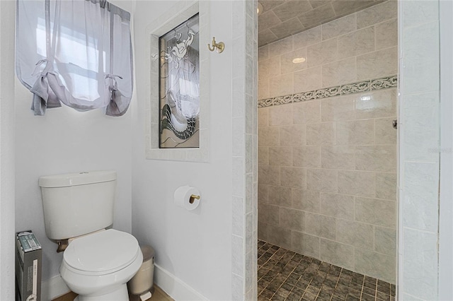 bathroom featuring tiled shower and toilet