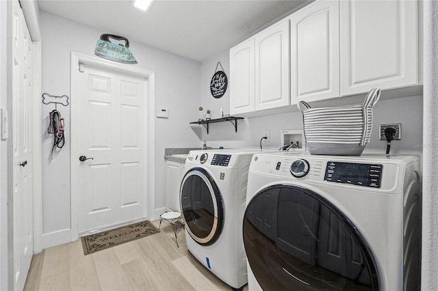 clothes washing area with washer and dryer, light hardwood / wood-style floors, and cabinets