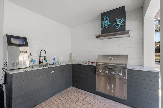 kitchen featuring dark brown cabinets, light stone counters, and sink