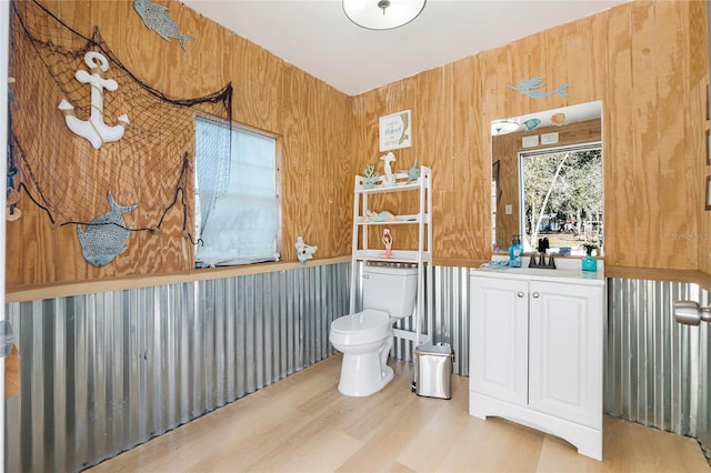 bathroom with hardwood / wood-style floors, vanity, toilet, and wooden walls